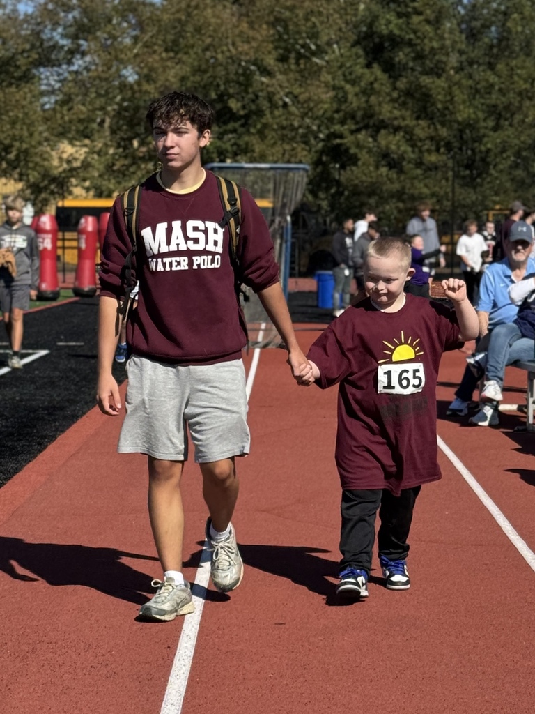 A young special olympian walking hand in hand with his big buddy.