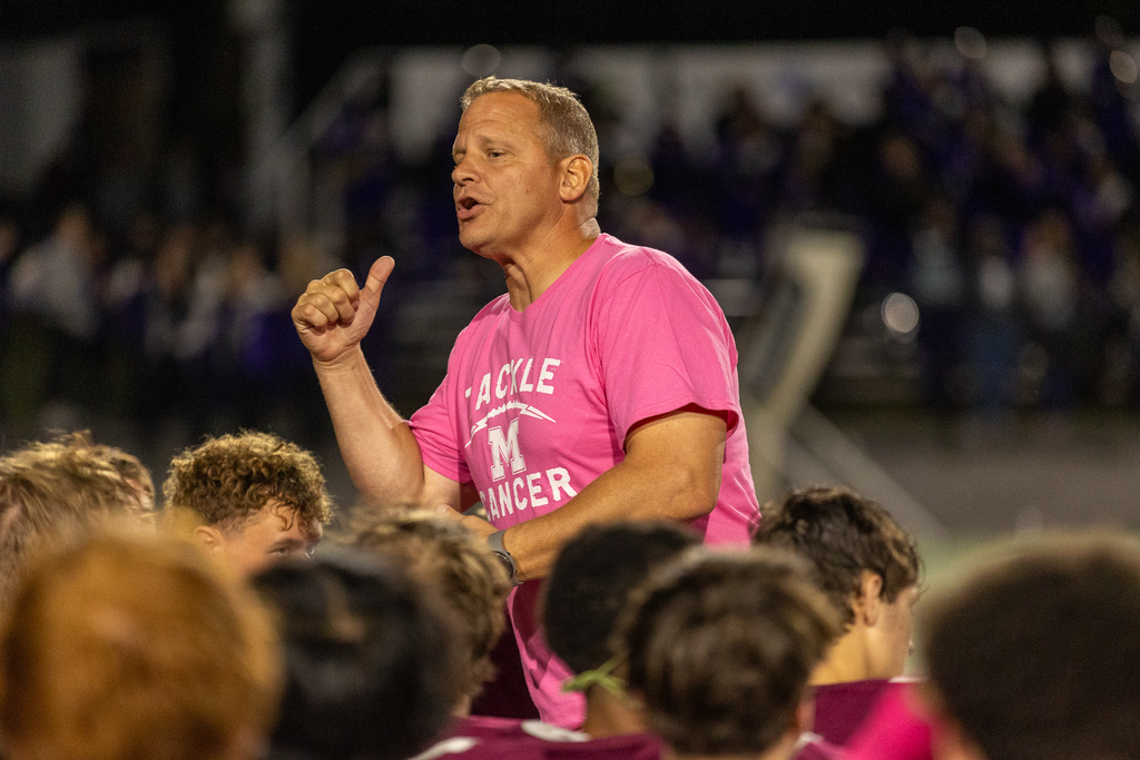Football coach providing instruction to his team.