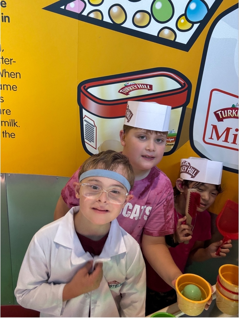 Students smiling at a toy kitchen.