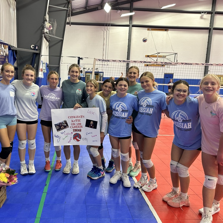 a group of girls surrounding their coach who is holding a sign