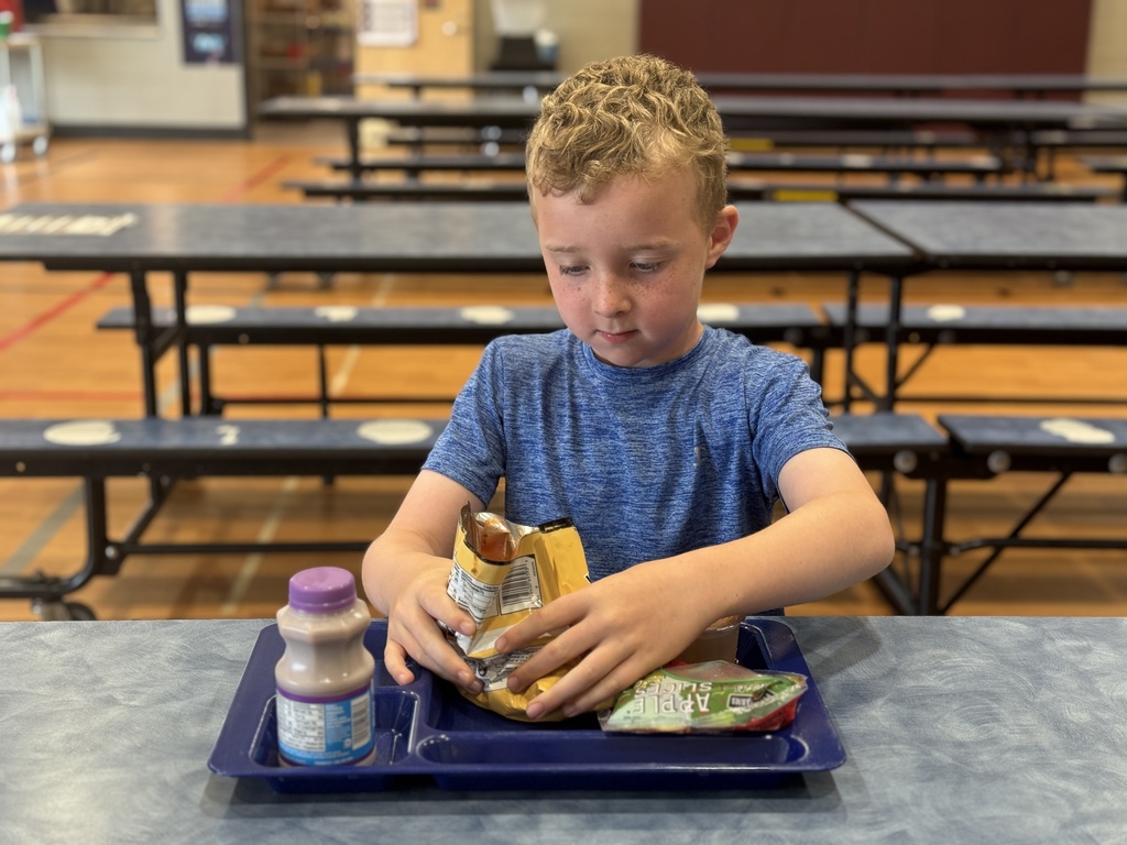 A young boy enjoying his lunch at school.