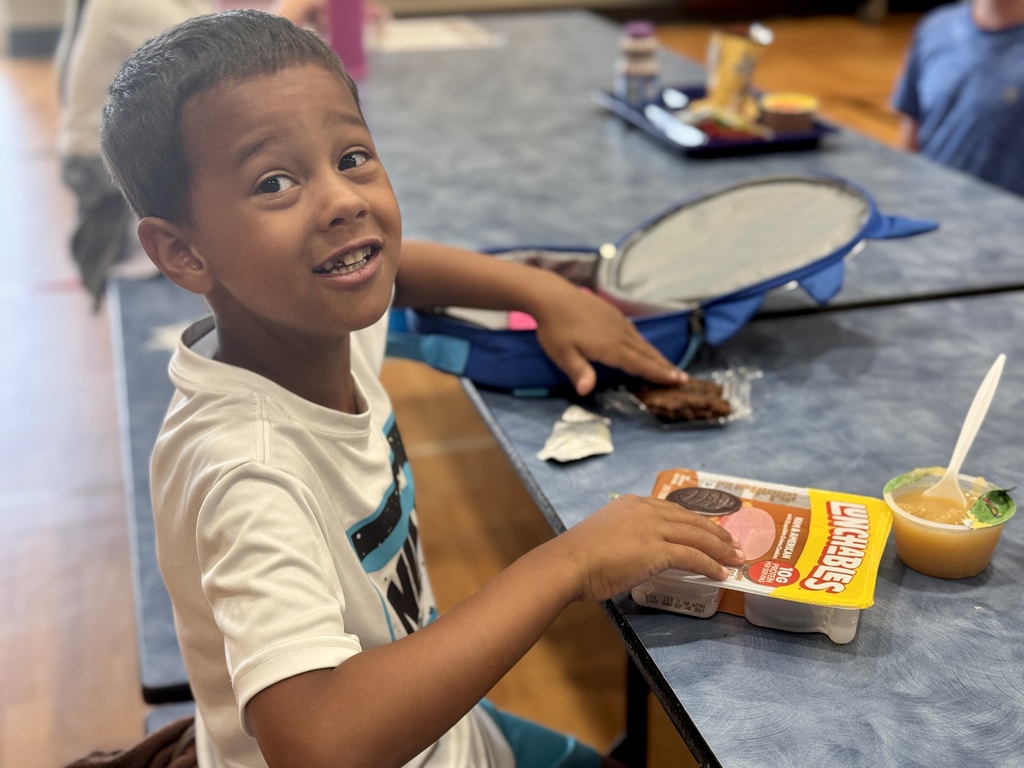 A young boy smiling in the school cafeteria.
