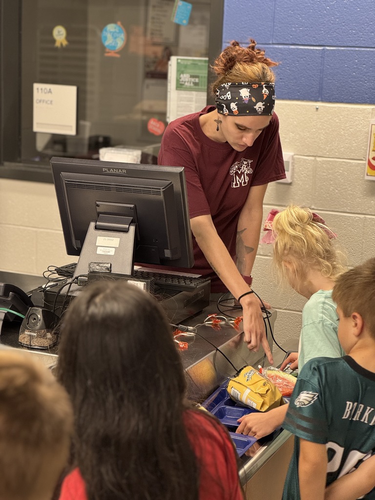 A staff member helping a young student in the cafeteria.