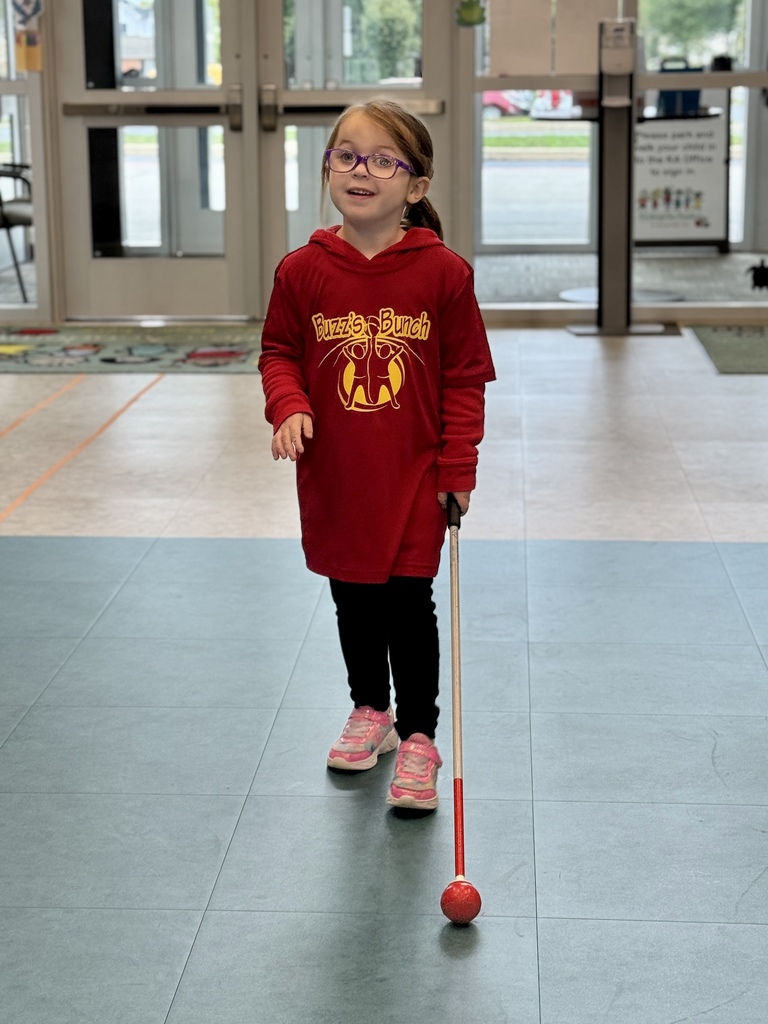 A young blind student navigating her school with her white cane.
