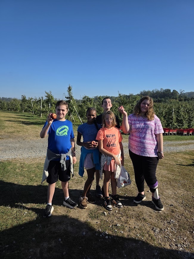 Students with apples they picked from a tree.