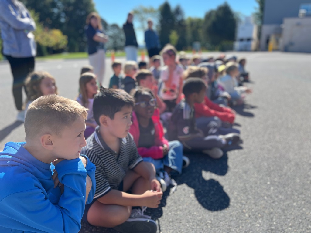 Elementary students sitting on ground while listening intently to fire prevention and safety tips.