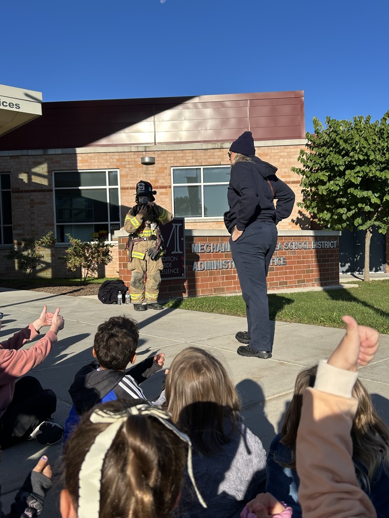 Firefighters showing fire safety equipment to students.