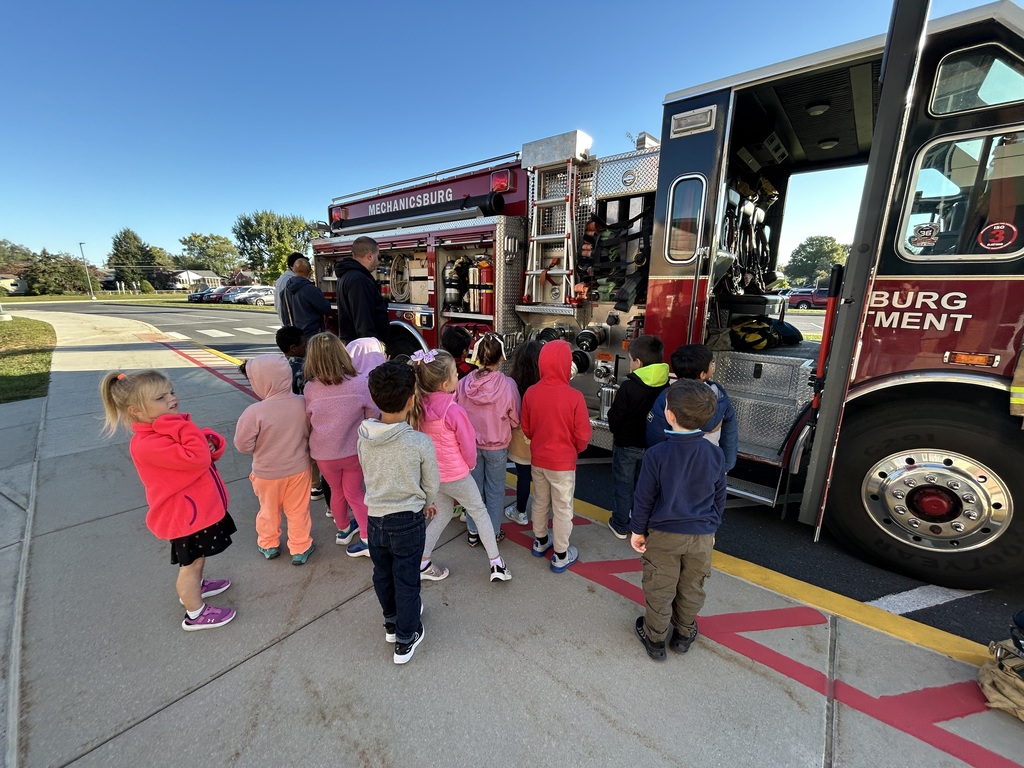 Elementary students looking at fire apparatus.