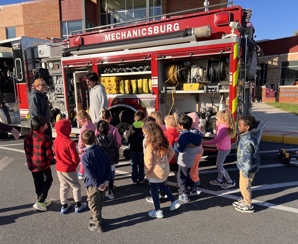 Elementary students looking at fire apparatus.