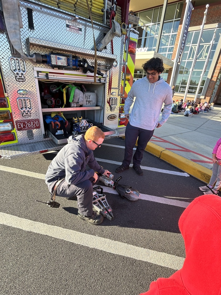 Firefighters showing fire safety equipment to students.