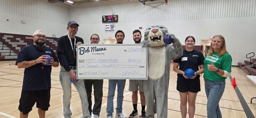 A group of adults standing with a big cardboard donation check.