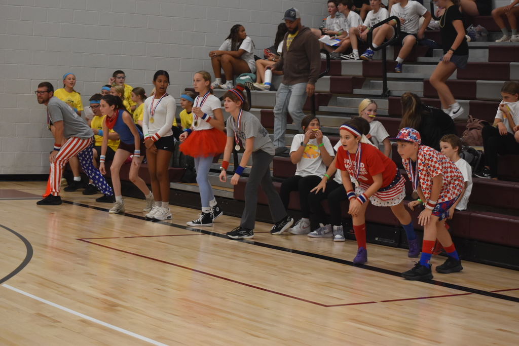 A team of students in colorful outfits getting ready to start a dodgeball game.