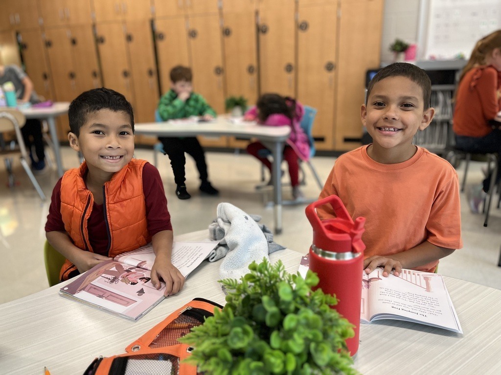 Two students in orange at a desk.