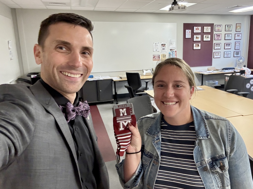 Two adults holding a pair of maroon striped, branded socks.