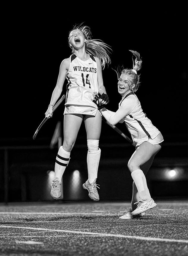 Two field hockey players jumping in the air.