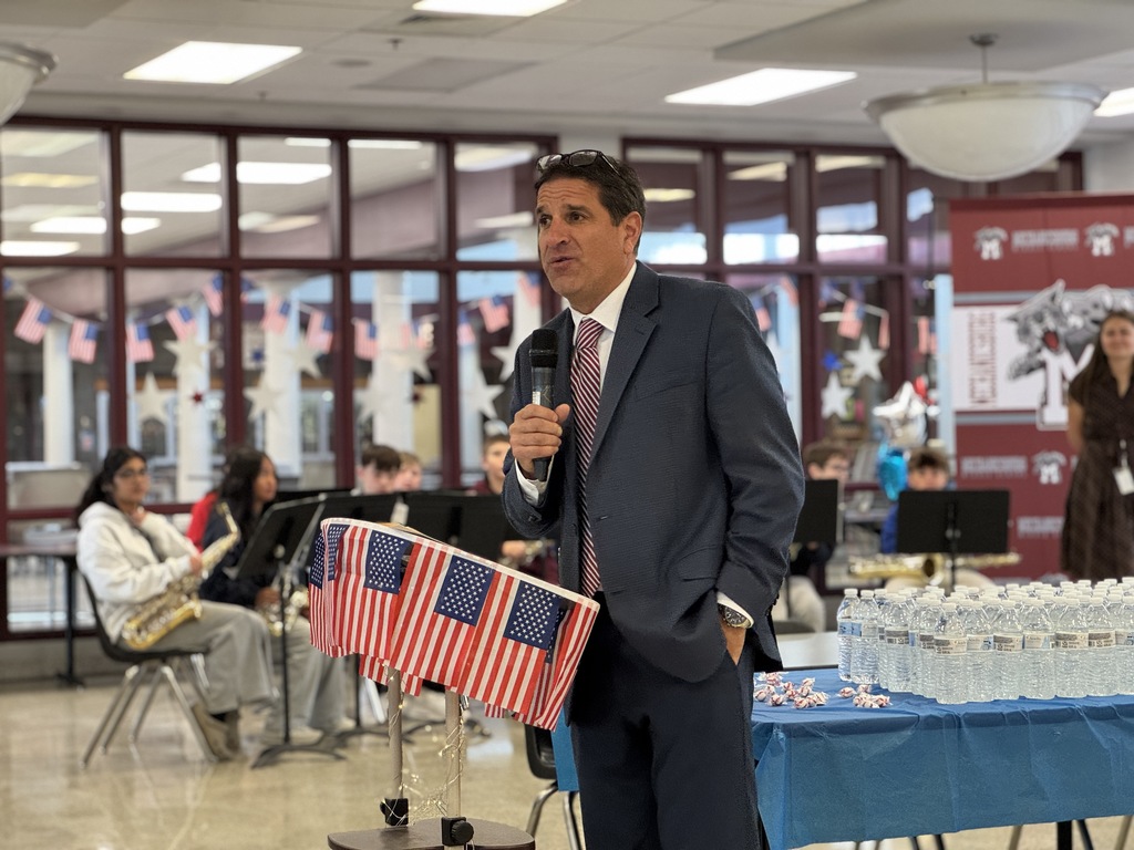 A man in a suit speaking before a crowd of veterans.