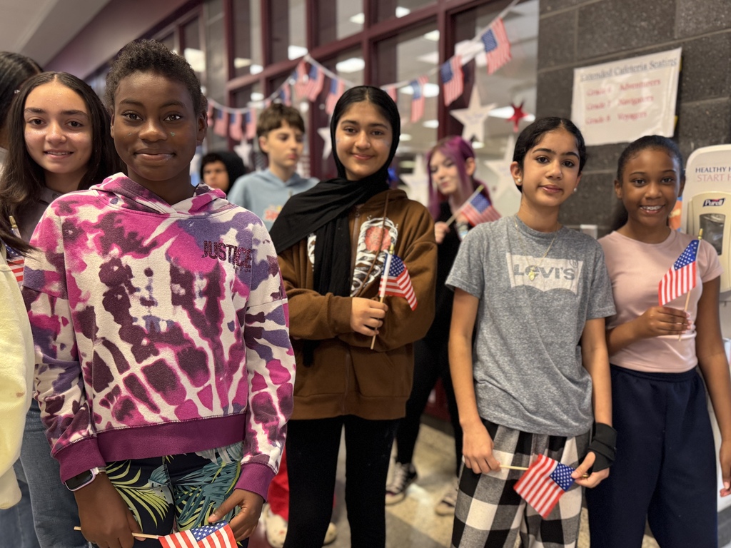 Students with flags waving at veterans