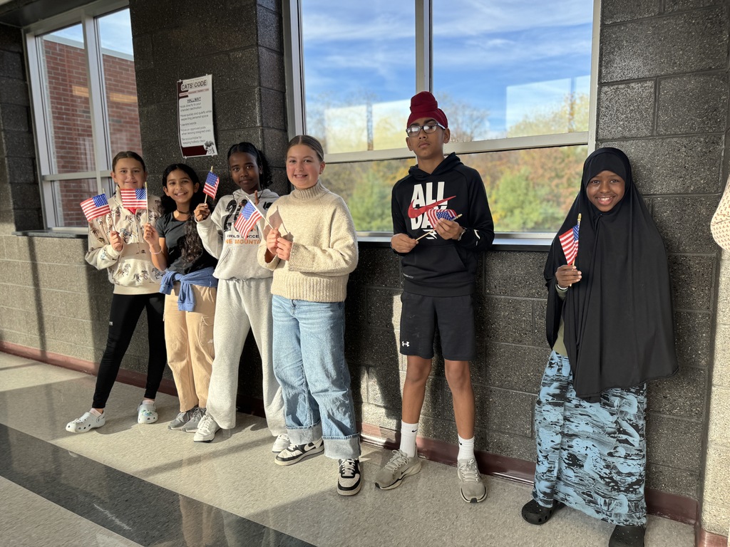 Students with flags, waving at veterans.