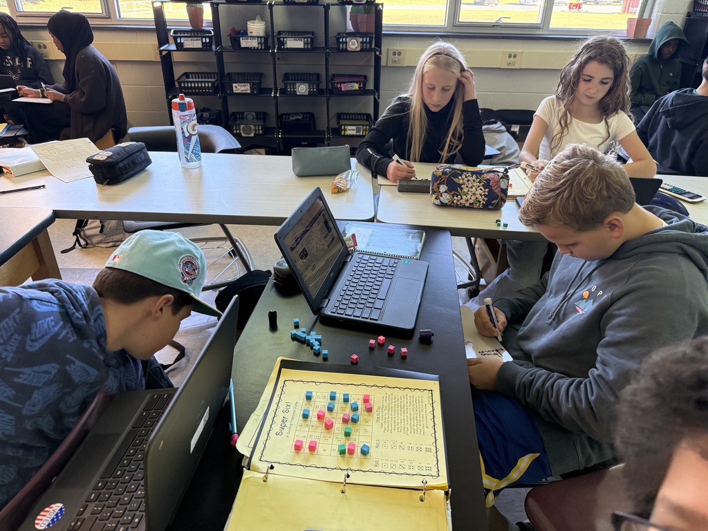 Three students playing a game in math to help learn fractions.