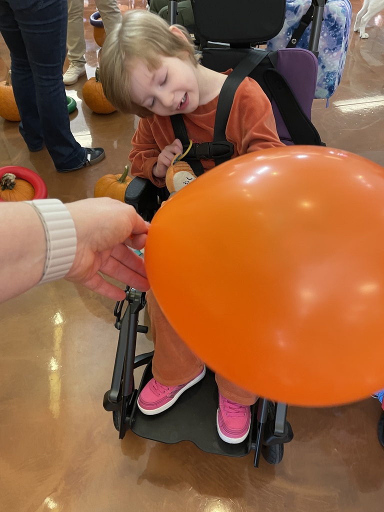 A student in a wheelchair with an orange balloon.