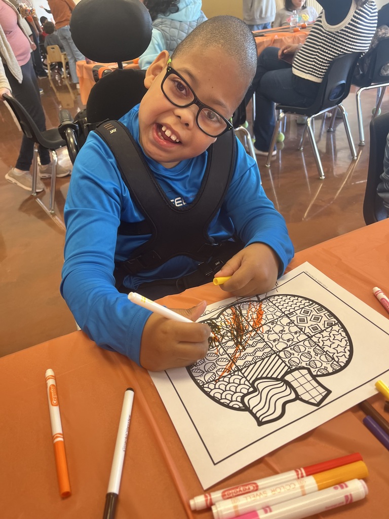 A student decorating a paper pumpkin.