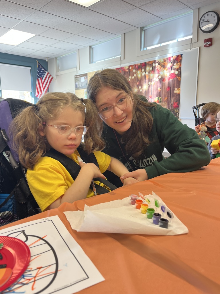 A young student with a row of paint on a table.