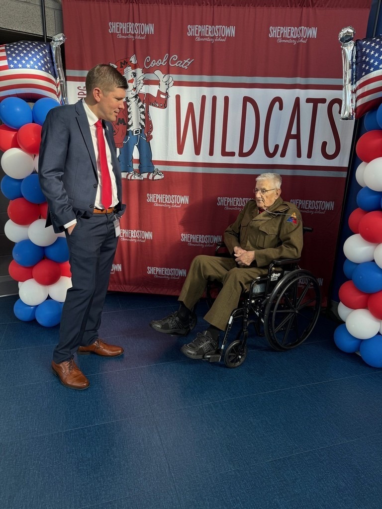 A school prinicpal talking to a veteran in a wheelchair on Veterans Day.