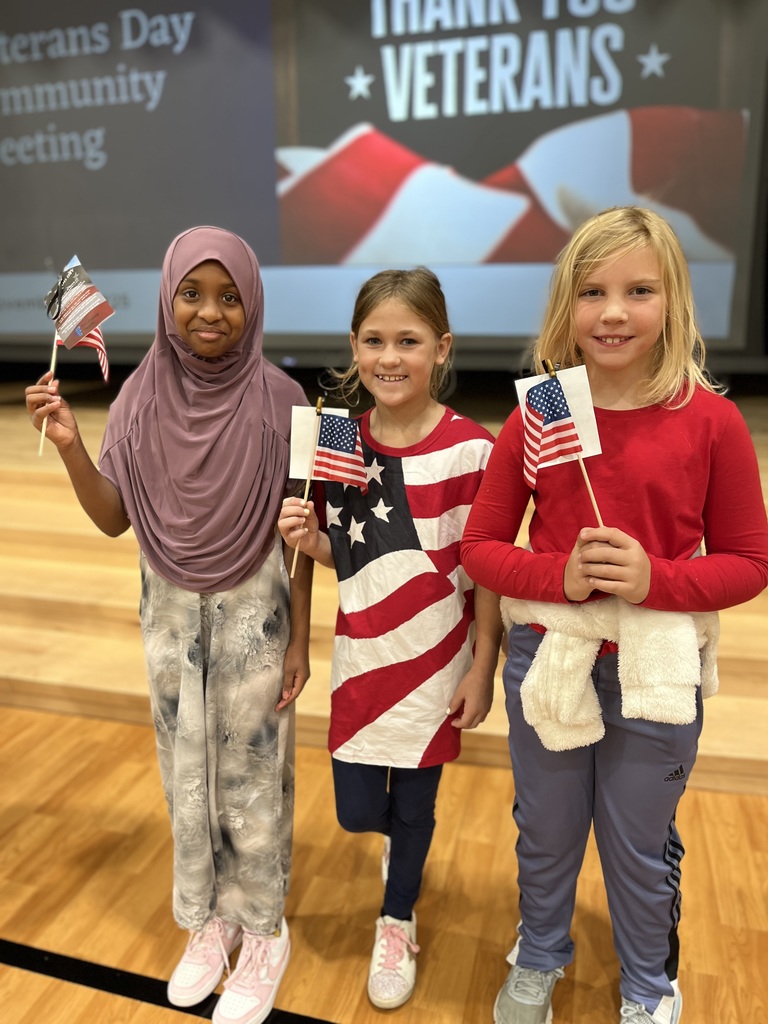 Students in red white and blue and holding american flags.