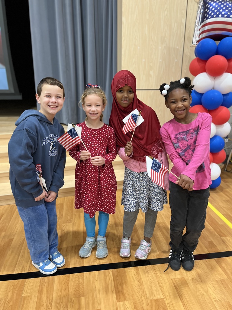 Students in red white and blue and holding american flags.