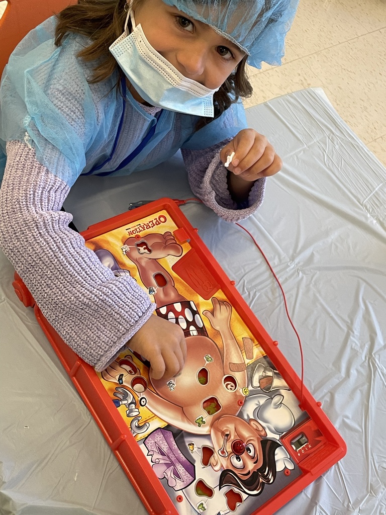 Student dressed as a play doctor and playing the game operation.
