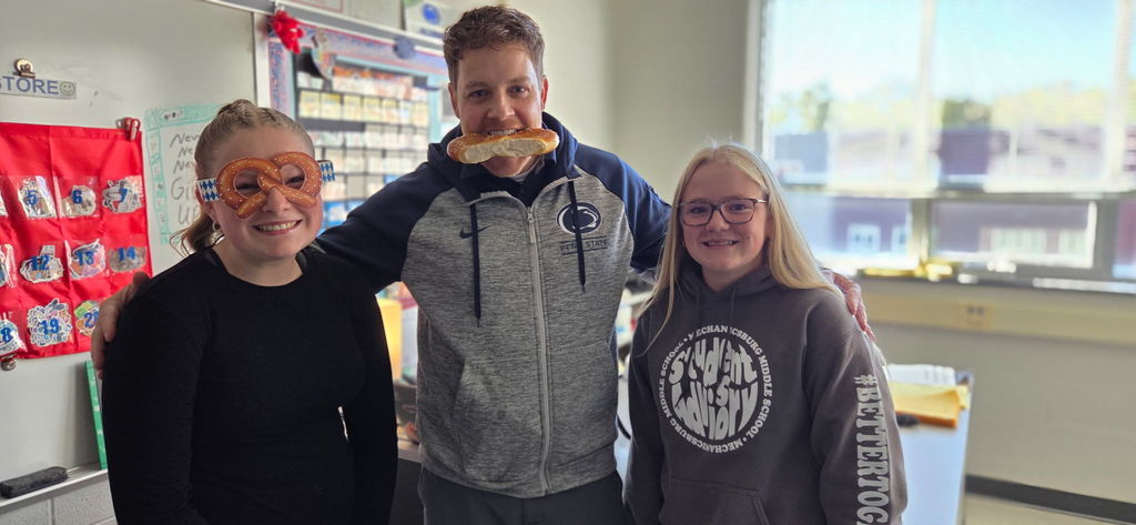 Students with a teacher who is biting on a soft pretzel.