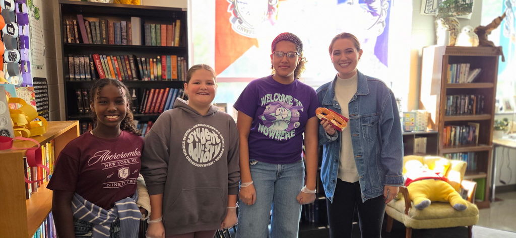 Students with a staff member who is holding a soft pretzel.