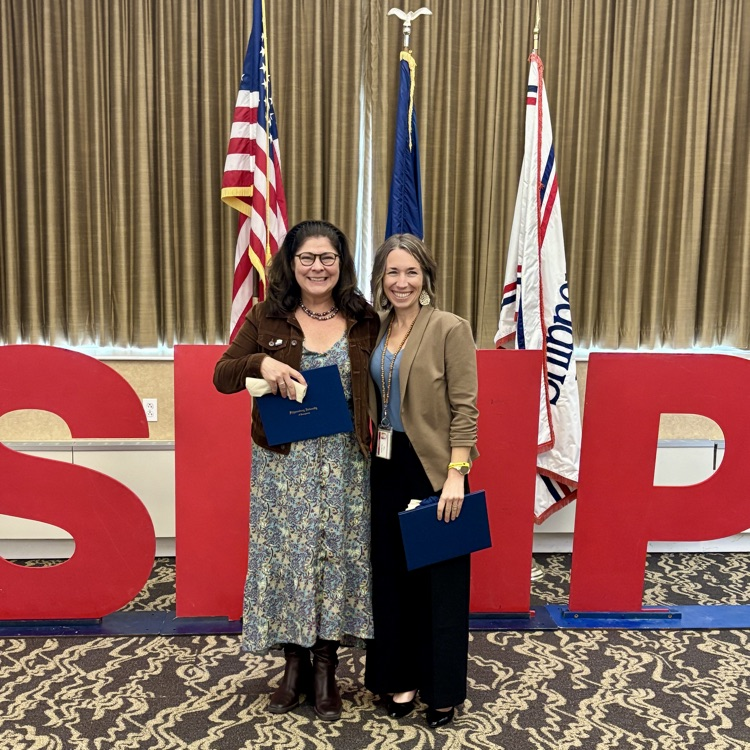 Two teachers holding recognition certificates