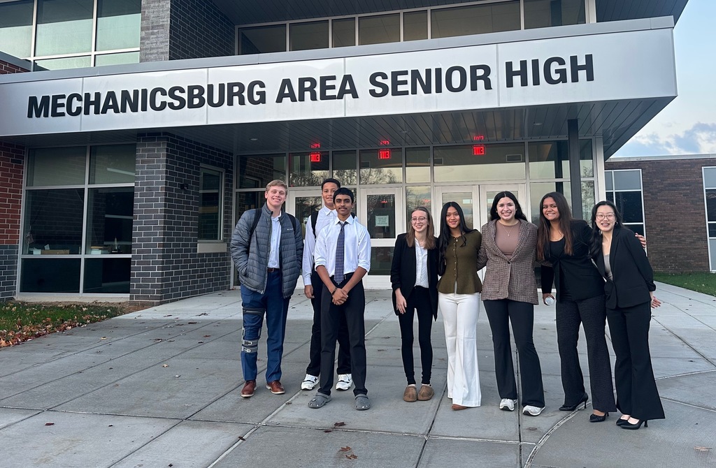 A group of high school students standing in front of the school.