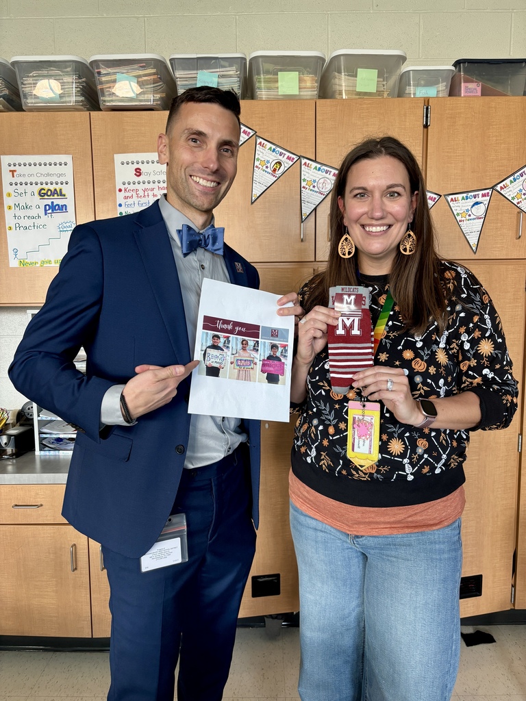 A man in a suit presenting a paid of branded socks to a teacher.