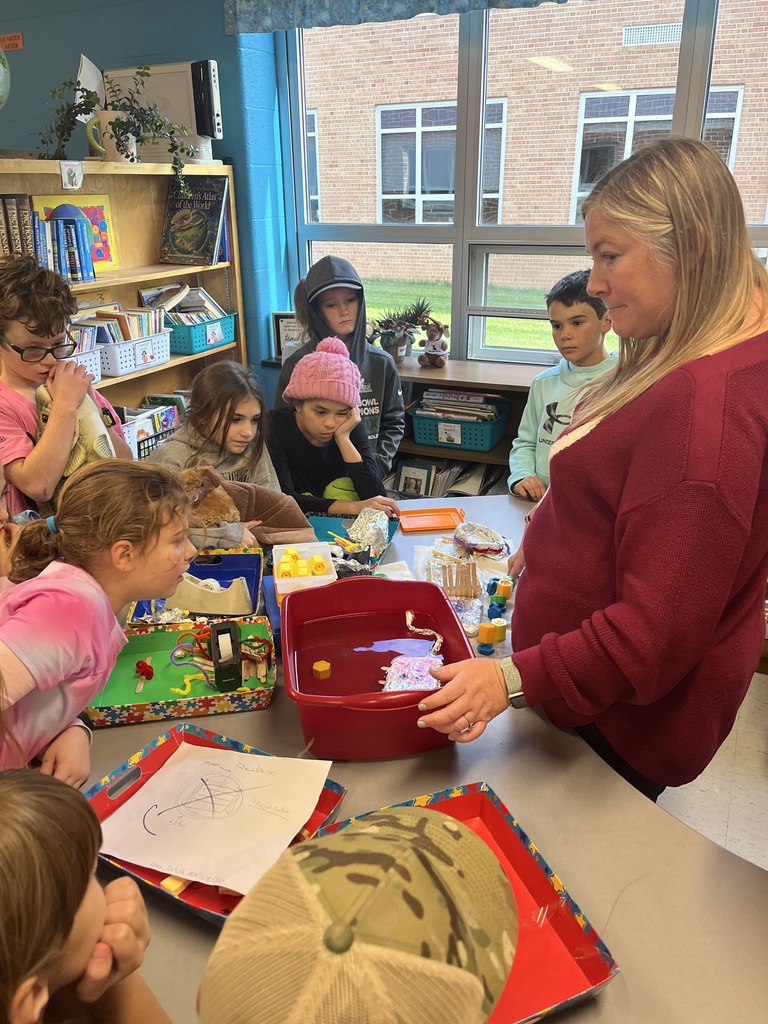 Students looking into a bucket full of water and items to see what sinks and what floats.