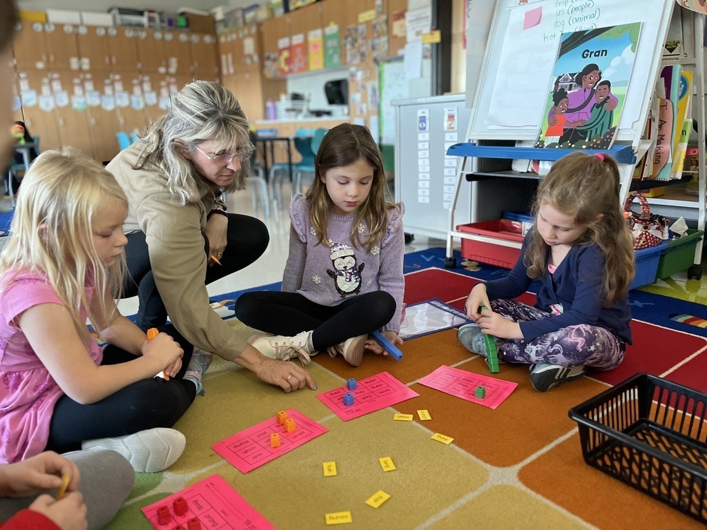 A teacher working on the floor with young students.