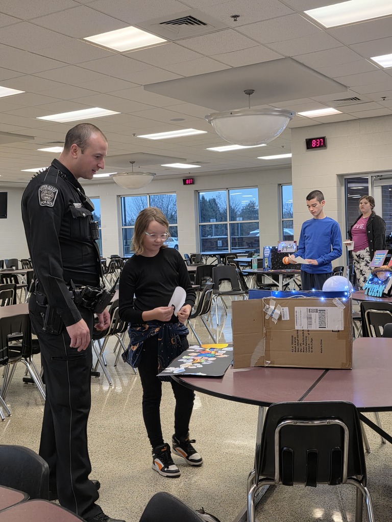 A student showing a school police officer a display on the solar system.