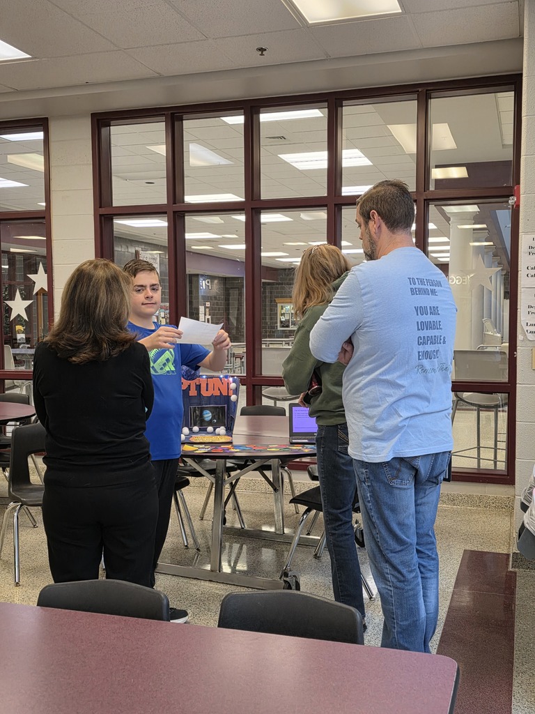 A student showing a educators a display on the solar system.