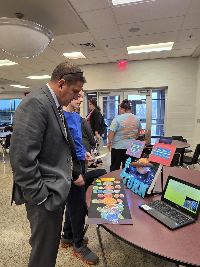 A student showing an educator a display on the solar system.
