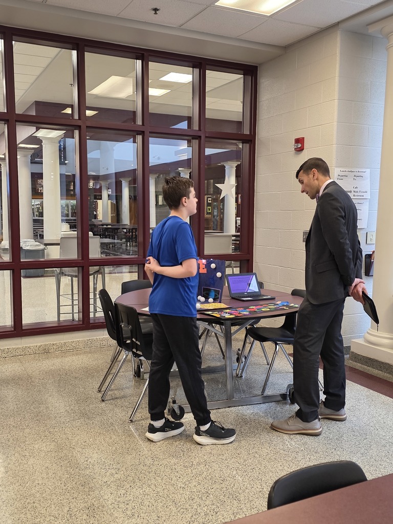 A student showing an educator a display on the solar system.