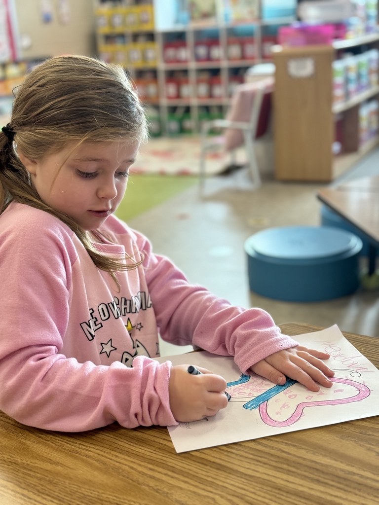 A young child coloring a picture of a butterfly they colored.