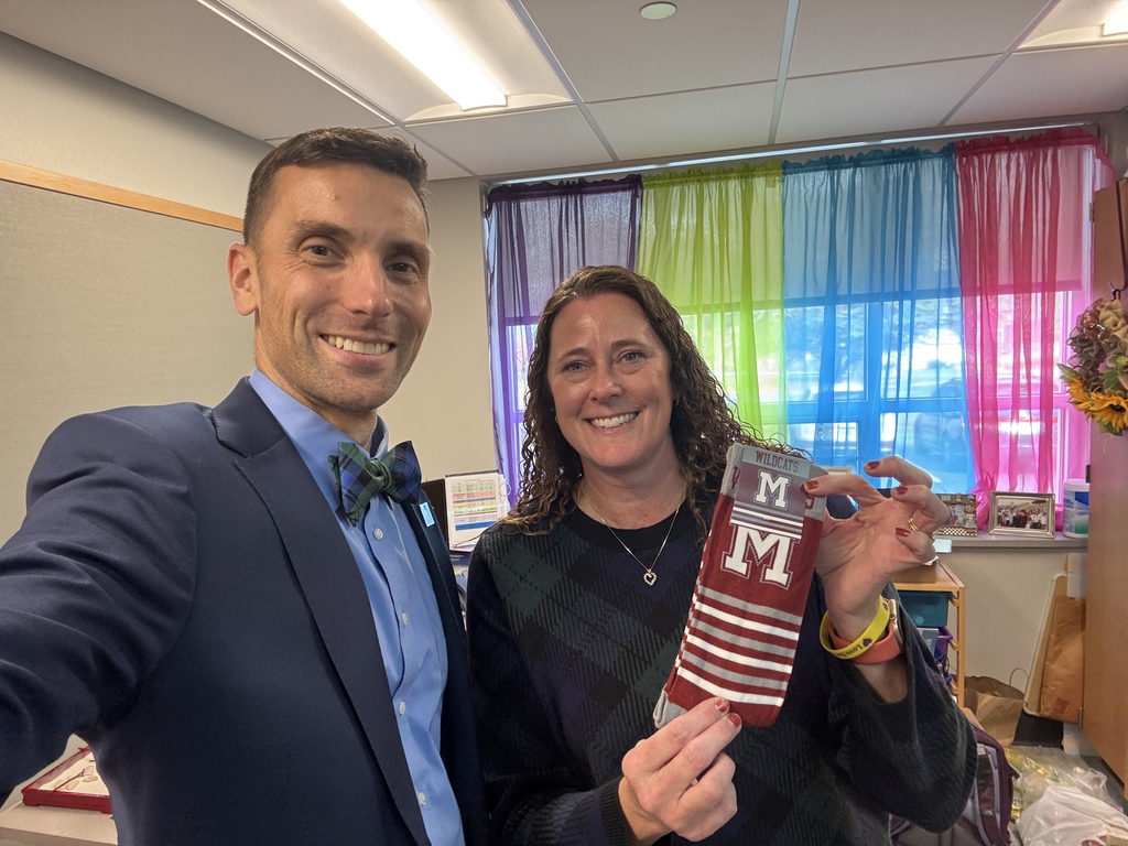 A man in a suit presenting a pair of branded socks to a staff member.