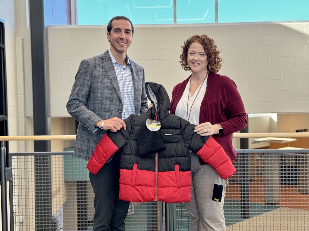 A man and a woman holding a red and black winter jacket.