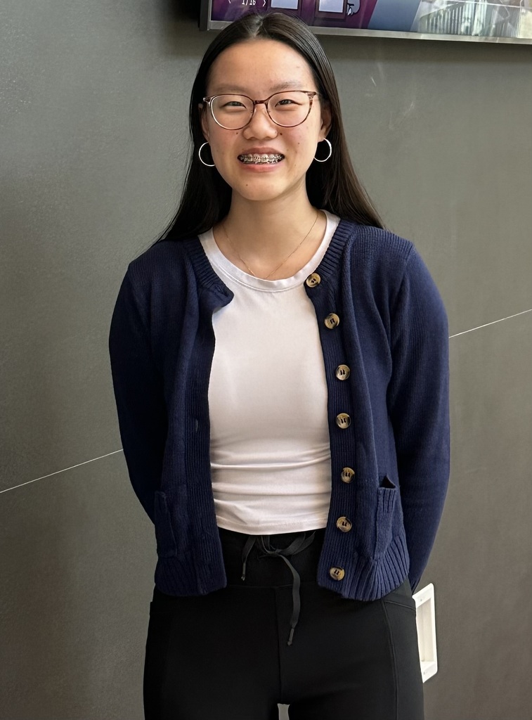 Headshot of student wearing white shirt and navy blue sweater.