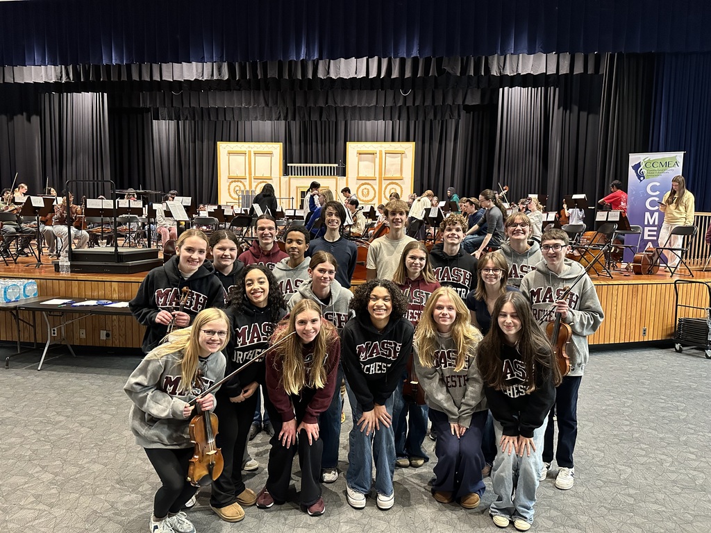 A group of student musicians posing in front of a stage.