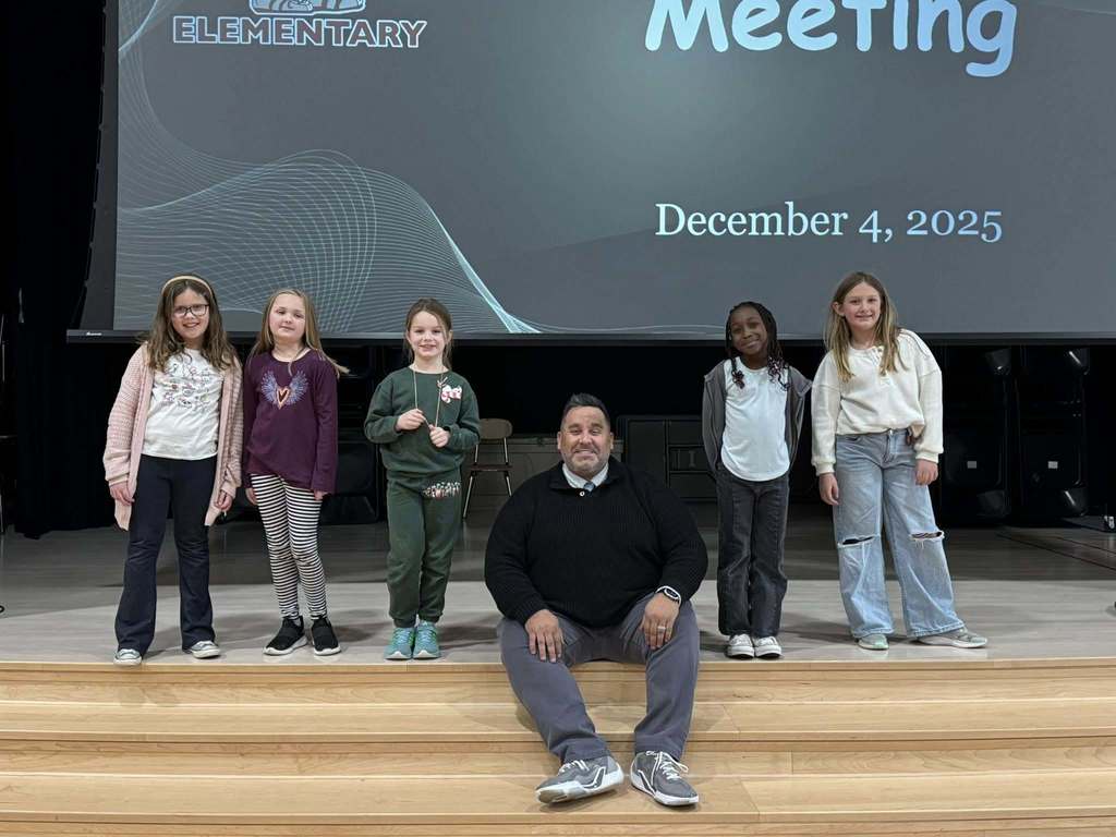 Students standing around a man who is seated.
