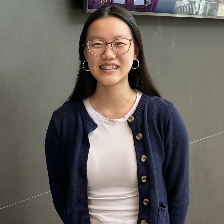 Headshot of student in a white tshirt and blue cardigan.