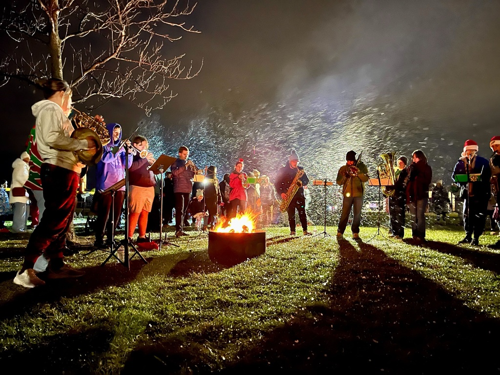 Marching band members performing around a campfire.
