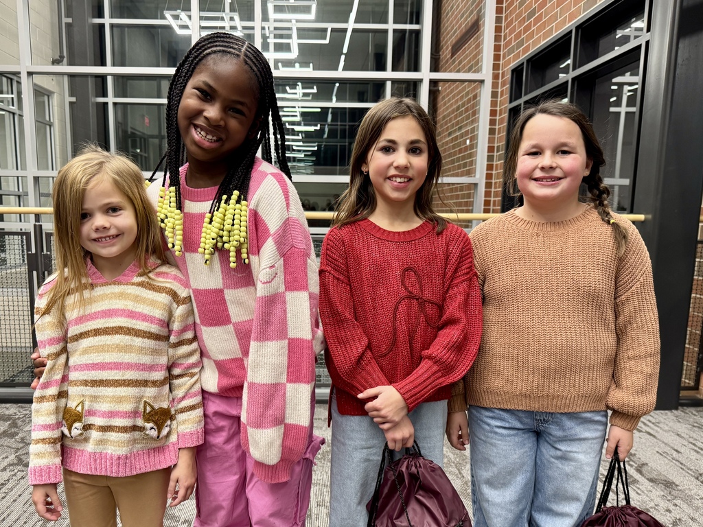 Four friends posing for a picture in the hallway of an office building.